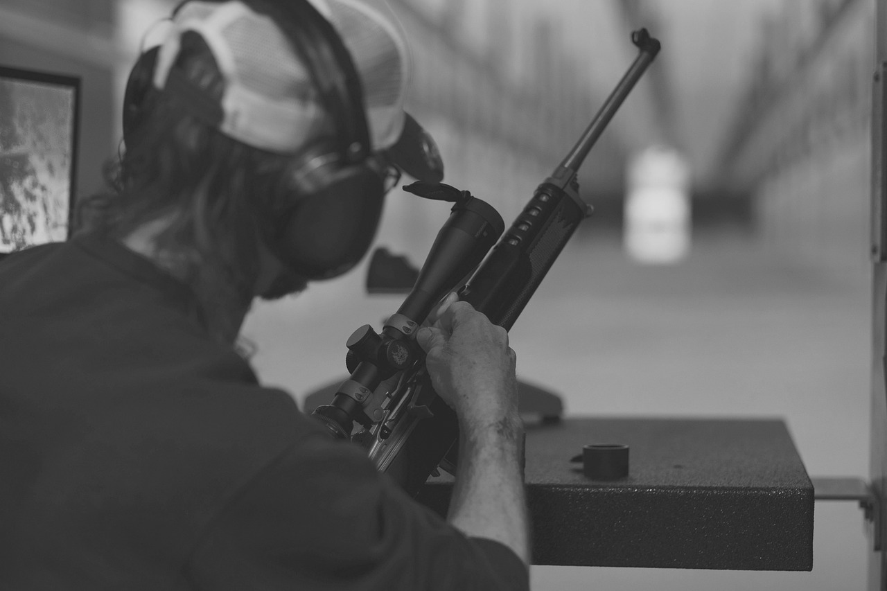 Person at indoor shooting range with rifle and scope